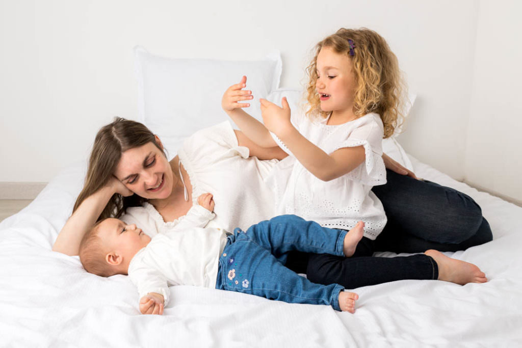 Séance photo cocooning maman bébé sur un lit comme à la maison, dans les Yvelines